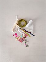 Paper, tape, ribbons, fabric, and beads on white background