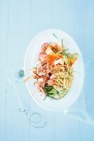 Vegetable salad with pasta and chicken skewers (seen from above)