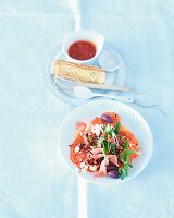 A salad with red rice, tomatoes, olives and ham