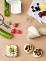 Bread with quark and cheese rolls topped with olives surrounded by ingredients