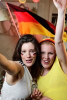 Portrait of two ecstatic women at a football game with Germany flag in background