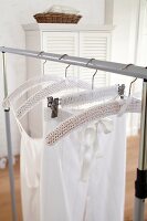 A white knitted cover hanging on a clothes hanger