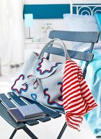 Cloth handbag with red and white striped scarf and diary on blue chair