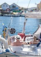 Tourist sitting on yacht at harbour, Fiskebackskil, Sweden