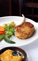 Fried veal with zucchini, broccoli, potato and rice tart on plate