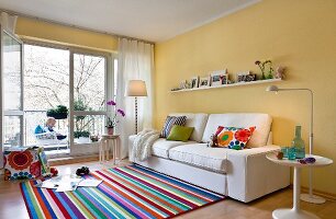 Living room with colourful striped carpet, sofa and beige wall