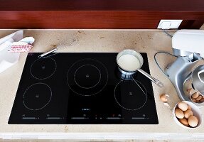Ceramic kitchen hob with bowl of eggs on worktop, elevated view