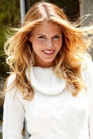 Portrait of attractive blonde woman wearing white turtleneck sweater, smiling
