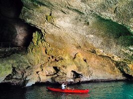 Person kayaking at Grotto in Gulf of Orosei, Sardinia, Italy