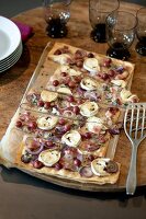 Tart with goat cheese, red onions and grapes on wood tray