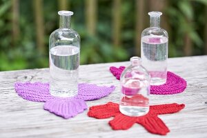Glass bottles on fall leaves and flower shaped crochet coasters