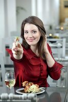 Portrait of pretty woman with brown hair in red blouse eating at restaurant, smiling