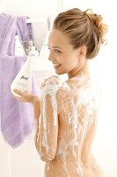 Junge blonde Frau mit Schaum unter der Dusche