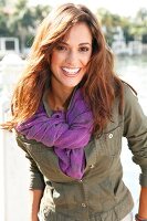 Portrait of attractive woman wearing green jacket and purple scarf, smiling