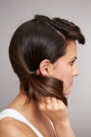Side view of brunette woman holding her hair