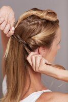 Close-up of blonde woman tightening her hair to prepare updo hairstyle