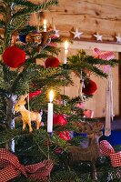 Weihnachtsbaum mit Tierfiguren, Pompons und Kerzen geschmückt