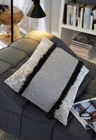 Grey embroidered velvet cushion on black sofa