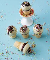 Cake pops in ice cream cones with chocolate glaze and colourful sugar sprinkles