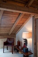 Reading corner with chair, table and lamp under wooden ceiling