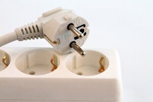 Close-up of plug on extension board against white background