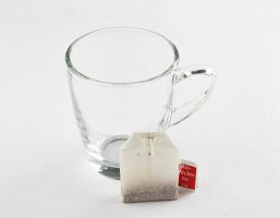 Glass tea cup with three tea bags on white background