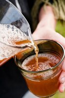 Apple juice being poured in glass at Hofmosterei Ellershausen in Hesse, Germany