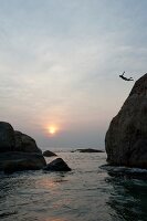Person diving from rocks in sea at sunset, Sri Lanka
