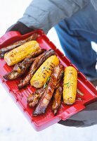 Grilled spare ribs and corn cobs on a red tray