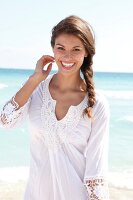 Dark-haired woman in a white blouse laughing by the sea