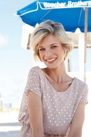 Portrait of happy blonde woman with short hair wearing polka dots dress, smiling