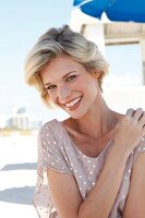 Portrait of happy blonde woman with short hair wearing polka dots dress, smiling