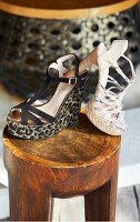 Wedges with leopard print and sandals with python print on wooden stool