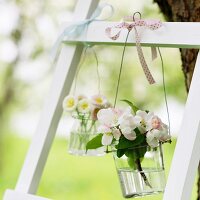 An Leiter hängende Vasen mit Apfelblüten und Tausendschön