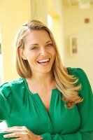 Portrait of happy blonde woman wearing green blouse, smiling