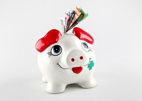 Close-up of piggy bank with various currency notes and coins stuck