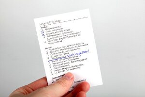 Close-up of hand holding travel checklist for vacation against white background