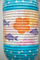 Close-up of person painting colourful lantern with flower and fish motif