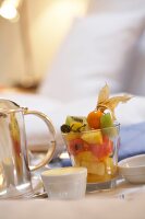 Breakfast tray on bed with fruit salad in glass in hotel rooms
