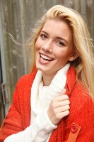Portrait of beautiful blonde woman with long hair in white and orange cardigan, smiling