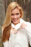 Portrait of beautiful blonde woman with long hair in white turtleneck sweater, smiling