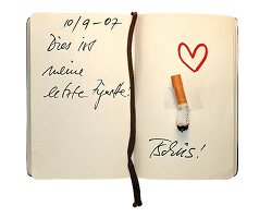 aufgeschlagenes Notizbuch mit ausgedrückter Zigarette und Herz