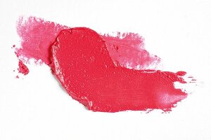 Pink lipstick smudged on white background