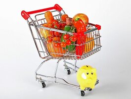Shopping cart with vegetables and fruits on white background