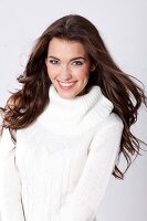 Portrait of beautiful woman with dark long hair wearing white turtleneck sweater, smiling