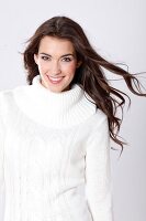 Portrait of beautiful woman with dark long hair wearing white turtleneck sweater, smiling