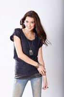 Portrait of pretty woman with long brown hair wearing blue blouse, jeans and long chain