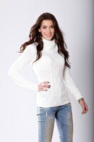 Portrait of pretty woman with dark hair in white turtleneck sweater and jeans, smiling