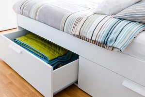 White double bed with drawers and striped blanket