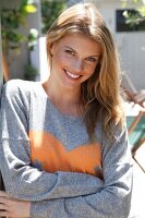 Portrait of beautiful blonde woman wearing gray sweater smiling with arms crossed